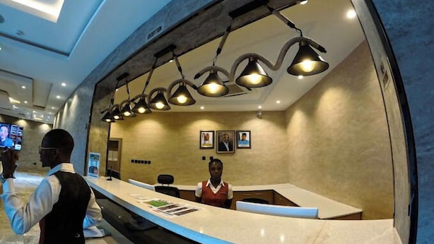 Zona de recepción de hotel con diseño moderno, que cuenta con un mostrador curvo e iluminación colgante.