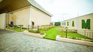 Un edificio con un patio empedrado, una zona cubierta y un muro con plantas.