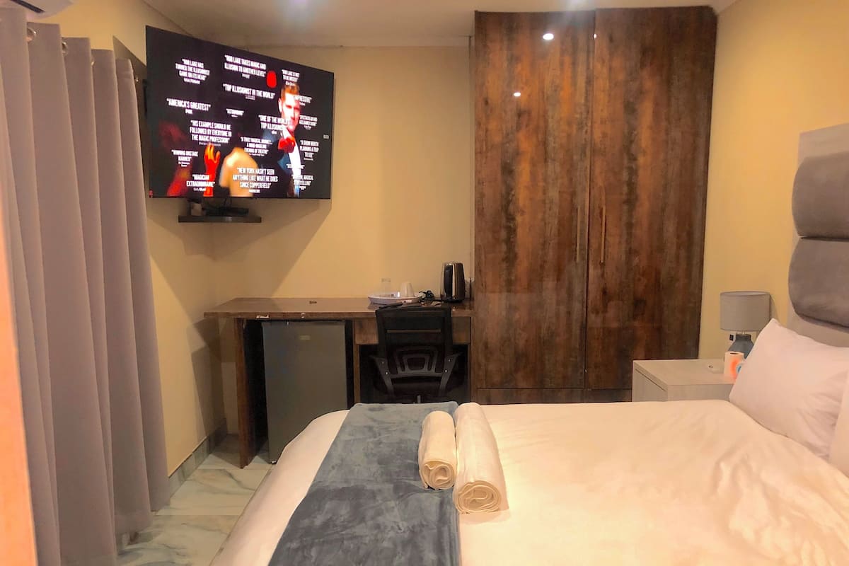 Una habitación de hotel con cama, escritorio, televisor y armario.