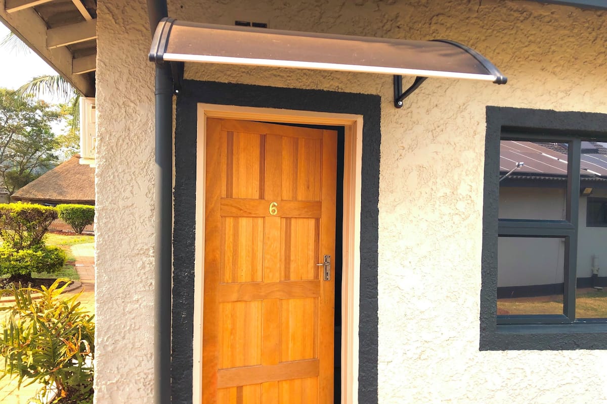 Puerta de madera con el número 6, pared con textura y una ventana a la derecha.
