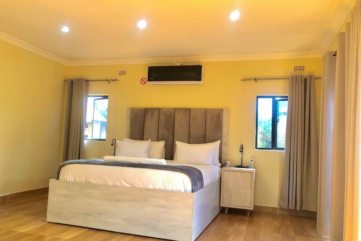 Un dormitorio moderno con una cama grande, mesitas de noche y un televisor montado en la pared.