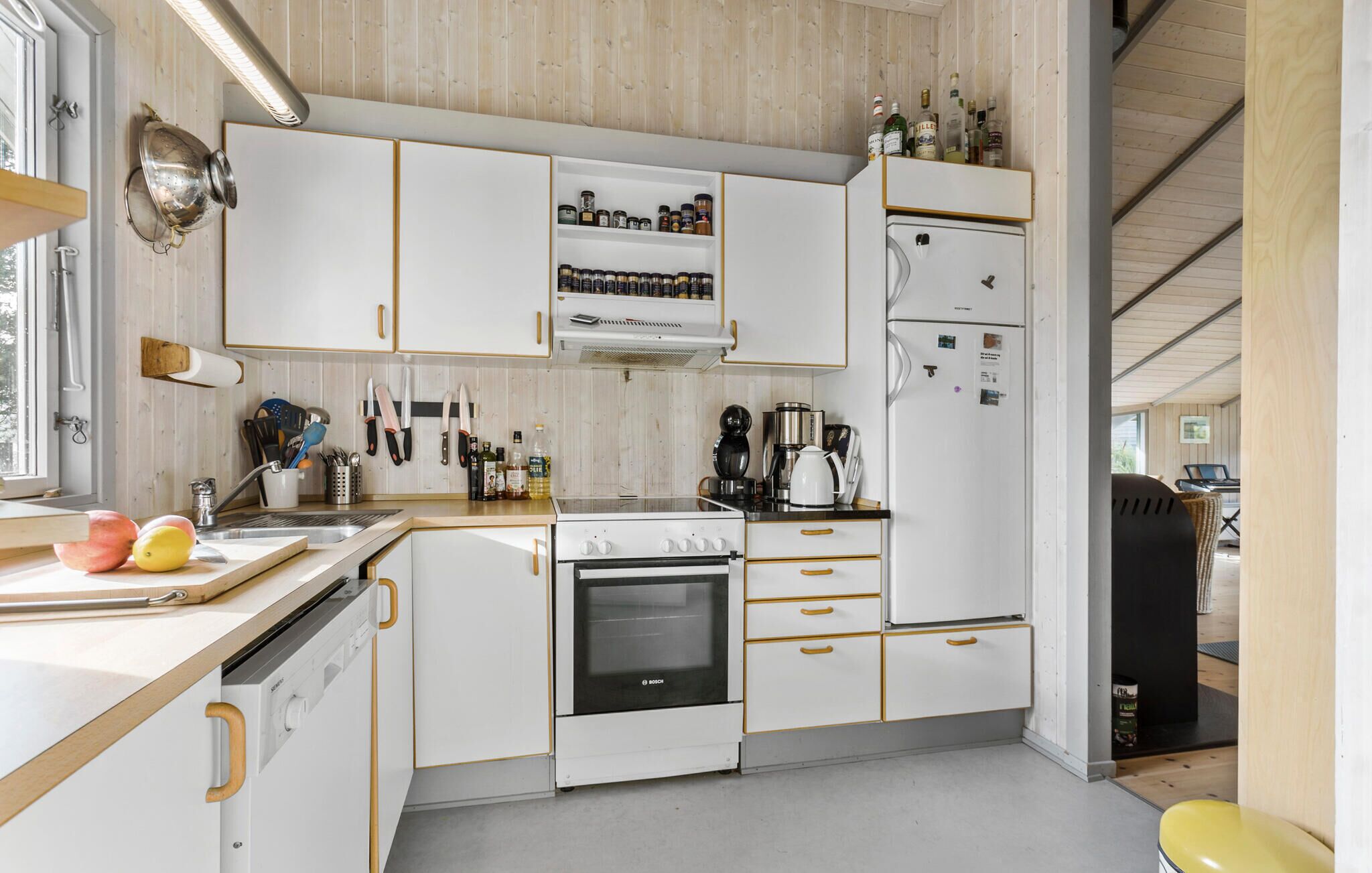 A modern kitchen with white cabinets, a Bosch oven, and a coffee maker.