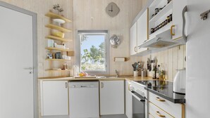 Een moderne keuken met witte kasten, houten planken en een raam dat natuurlijk licht binnenlaat.
