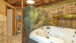 Ein Badezimmer mit Steinwand, Holzboden und einer Badewanne.