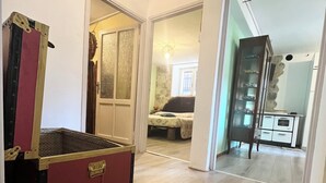 A hallway with a vintage trunk, a bed with a stone wall, and a cabinet with toy cars. - SMILE          (Berzo)