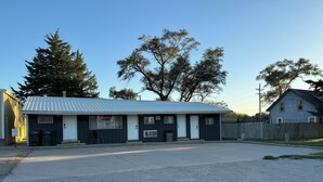 Un motel avec un toit en métal, deux portes et un parking recouvert de gravier.