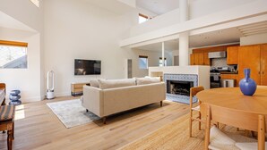 Un amplio espacio de sala con un sofá, una mesa de comedor y una chimenea.