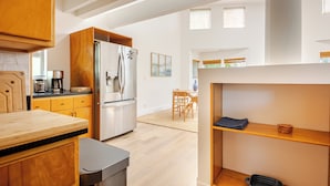 Una cocina moderna con armarios de madera, un refrigerador de acero inoxidable y un comedor con mesa y sillas de madera.