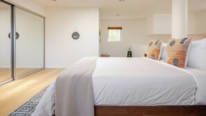 Un dormitorio con una cama grande, un ventanal corredero, un ventano y un techo con tragaluces.