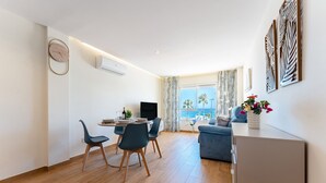 Ein modernes Wohnzimmer mit Essbereich, einem Flachbildfernseher und Meerblick.