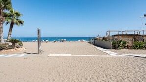 Une plage bordée de palmiers, avec des parasols, et un ciel bleu azur.