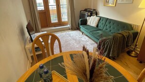 Ein Essbereich mit einem runden Tisch, Stühlen und einer Vase mit Trockenpflanzen. Im Hintergrund befinden sich ein Sofa und eine Lampe.