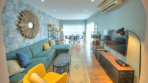 A modern living room with a sectional sofa, a coffee table, and a TV on a wooden stand. - Stylish, large 3bedroom, seafront terrace GOSLM-13 (Sliema)