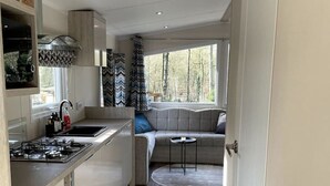 A modern kitchen with a built-in stove, a window with curtains, and a seating area with a rug. - New luxury chalet at 't Veluws Hof AC/kids++/wifi (Hoenderloo)