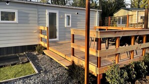 A mobile home with a wooden deck and a small outdoor area with a trampoline. - New luxury chalet at 't Veluws Hof AC/kids++/wifi (Hoenderloo)