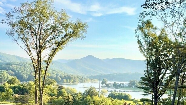 Een terras met uitzicht op een rivier, bergen en een bebost landschap.