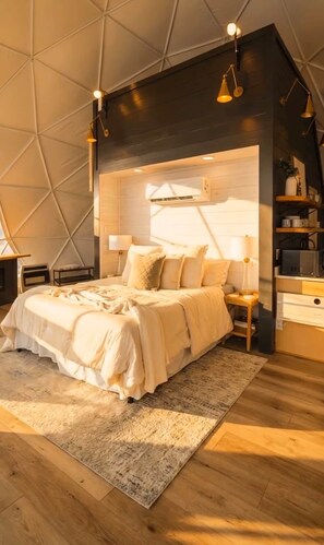 Une chambre moderne avec un plafond au design géométrique, un lit agrémenté de plusieurs coussins, des lampes de chevet et un système de climatisation intégré.