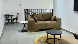 A modern living room with a sofa, two tables, and a TV mounted on the wall.