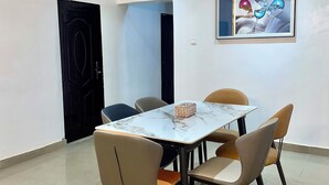 A dining area with a marble table, four chairs, and a hanging light fixture.