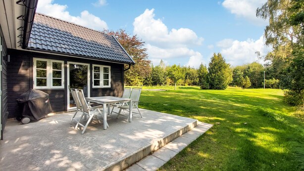 Una piccola casa con patio, tavolo e sedie, e un barbecue.