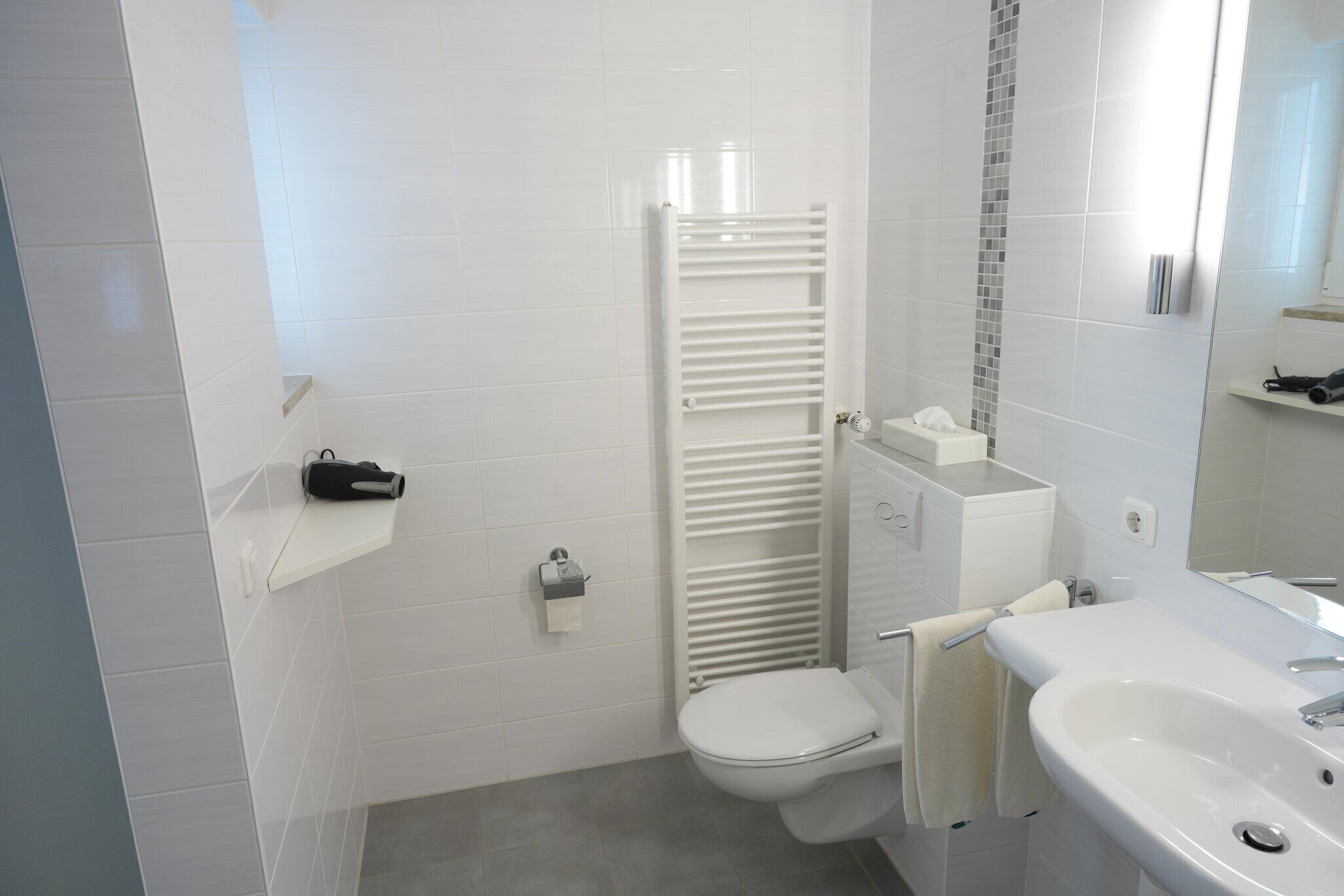 Une salle de bain moderne équipée de toilettes, d’un lavabo et d’un porte-serviettes.