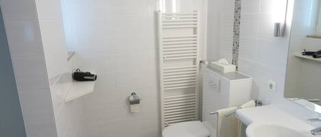 Une salle de bain moderne équipée de toilettes, d’un lavabo et d’un porte-serviettes.