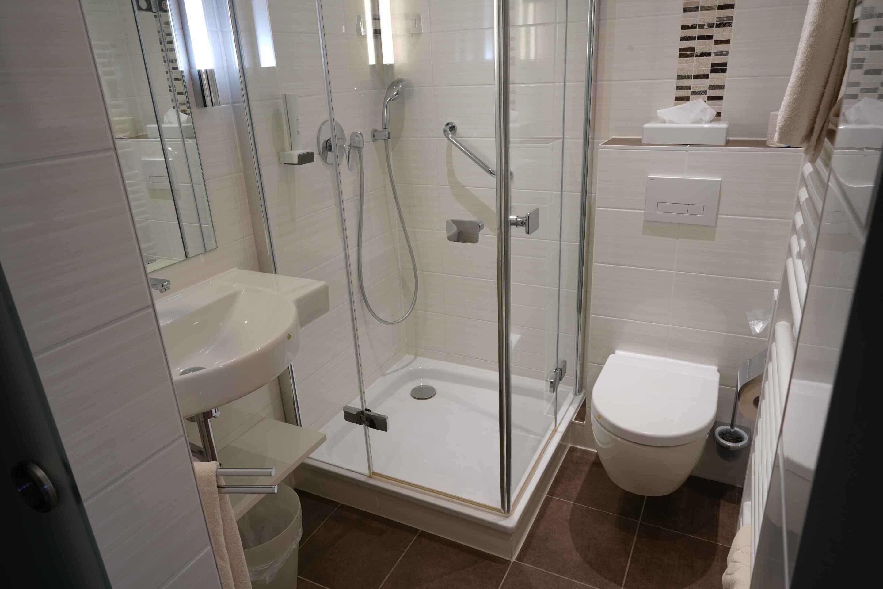 Une salle de bain moderne avec une douche à parois de verre, un lavabo blanc et des toilettes.