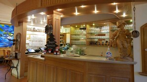 A bar area with a wooden counter, a statue, and shelves with glassware. - G. Hotel Müller (Lichtenfels)