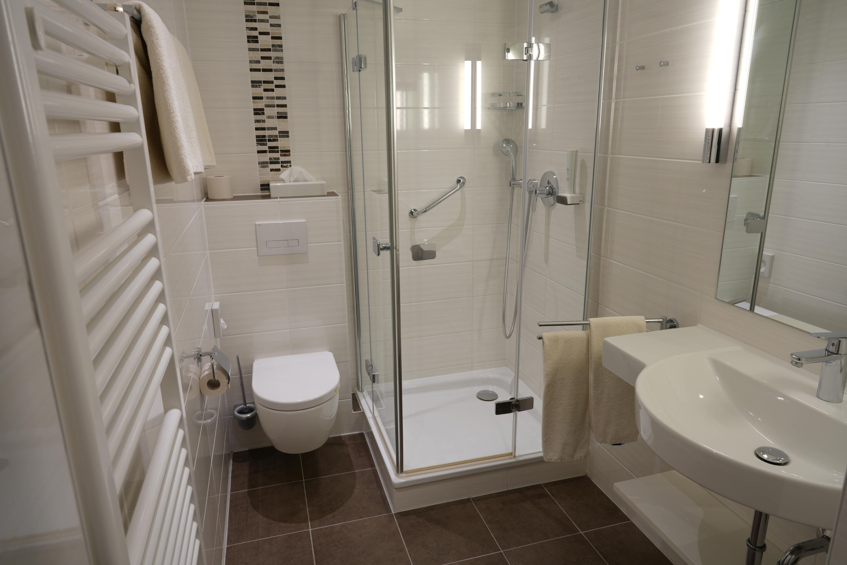 A modern bathroom with a glass-enclosed shower, a white sink, and a toilet.