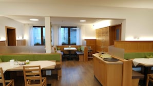 A restaurant with booths and tables, wooden flooring, and a view of the outdoors through large windows. - G. Hotel Müller (Lichtenfels)