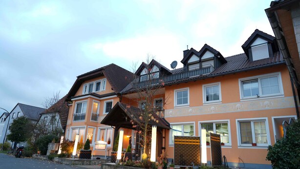 A multi-story building with a traditional architectural style, featuring a prominent entrance with a covered porch and a satellite dish on the roof. - G. Hotel Müller (Lichtenfels)