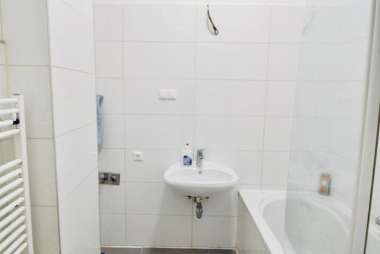 A bathroom with a white sink, a bathtub, and a towel rack.