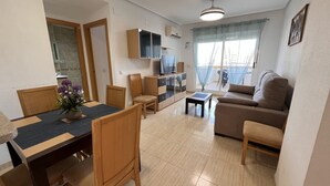 A modern living room with a sofa, a dining table with chairs, a TV, and a small table. - ACV - Costa Azahar II-2nd floor line 6 north 2 (OROPESA)