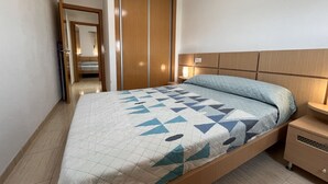 A bedroom with a bed, a nightstand, a wardrobe, and a mirror. - ACV - Costa Azahar II-2nd floor line 6 north 2 (OROPESA)