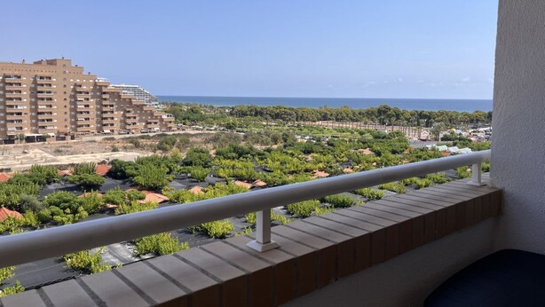 A balcony with a view of a coastal area, including buildings and greenery. - ACV - Costa Azahar II-2nd floor line 6 north 2 (OROPESA)
