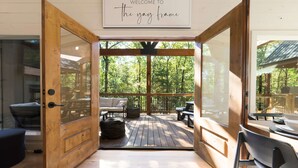 A wooden-framed door leading to an outdoor deck with a sofa, chairs, and a table.