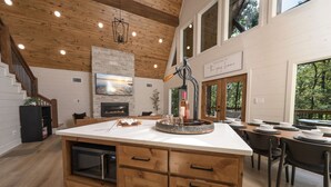 A spacious kitchen with a large island, wooden cabinets, and a stone backsplash.