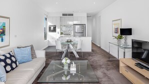 A modern living room with a glass coffee table, a sofa, and a TV on a wooden stand. - Swainson on Hindmarsh (Adelaide)