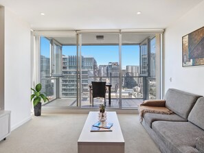 A modern living room with a large sliding glass door leading to a balcony with a city view. - Swainson on Balfours (Adelaide)