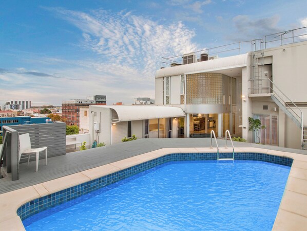 A rooftop pool with a view of the cityscape, a covered outdoor seating area, and a modern building with a glass facade. - Swainson on Waymouth (Adelaide)