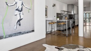 Una cucina moderna con un'area bar, un grande quadro appeso alla parete e un tavolo in vetro sullo sfondo.