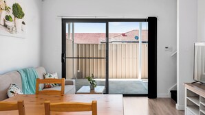 Eine moderne Wohnung mit Essbereich, einer Couch, einem Fernseher und einer Schiebetür zu einem Balkon.