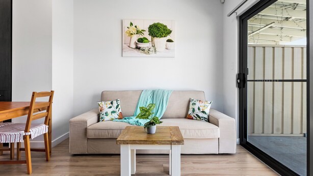 Ein modernes Wohnzimmer mit einer Couch, einem Holztisch und einem Essbereich mit Stühlen.