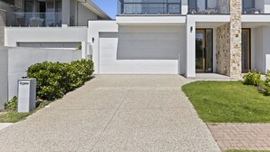 A modern two-story house with a garage, a stone facade, and a well-maintained lawn. - Swainson on Lexington (Henley Beach South)