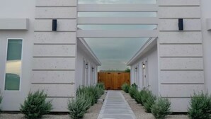 A modern building with a covered walkway leading to a wooden door. - Modern 2-bed, 2-bath home with WiFi, Smart TVs, coffee, tea, and cereal included (Weslaco)