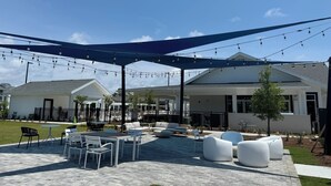 An outdoor patio area with seating, string lights, and a covered section. - King Condo In Panama City Beach Resort Amenities Hot Tub Downtown Pier Park (Panama City)