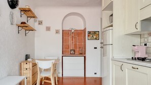 A compact kitchen with white cabinets, a wooden table, and chairs.