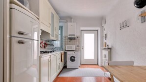 A compact kitchen with a washing machine, a microwave, and a refrigerator.