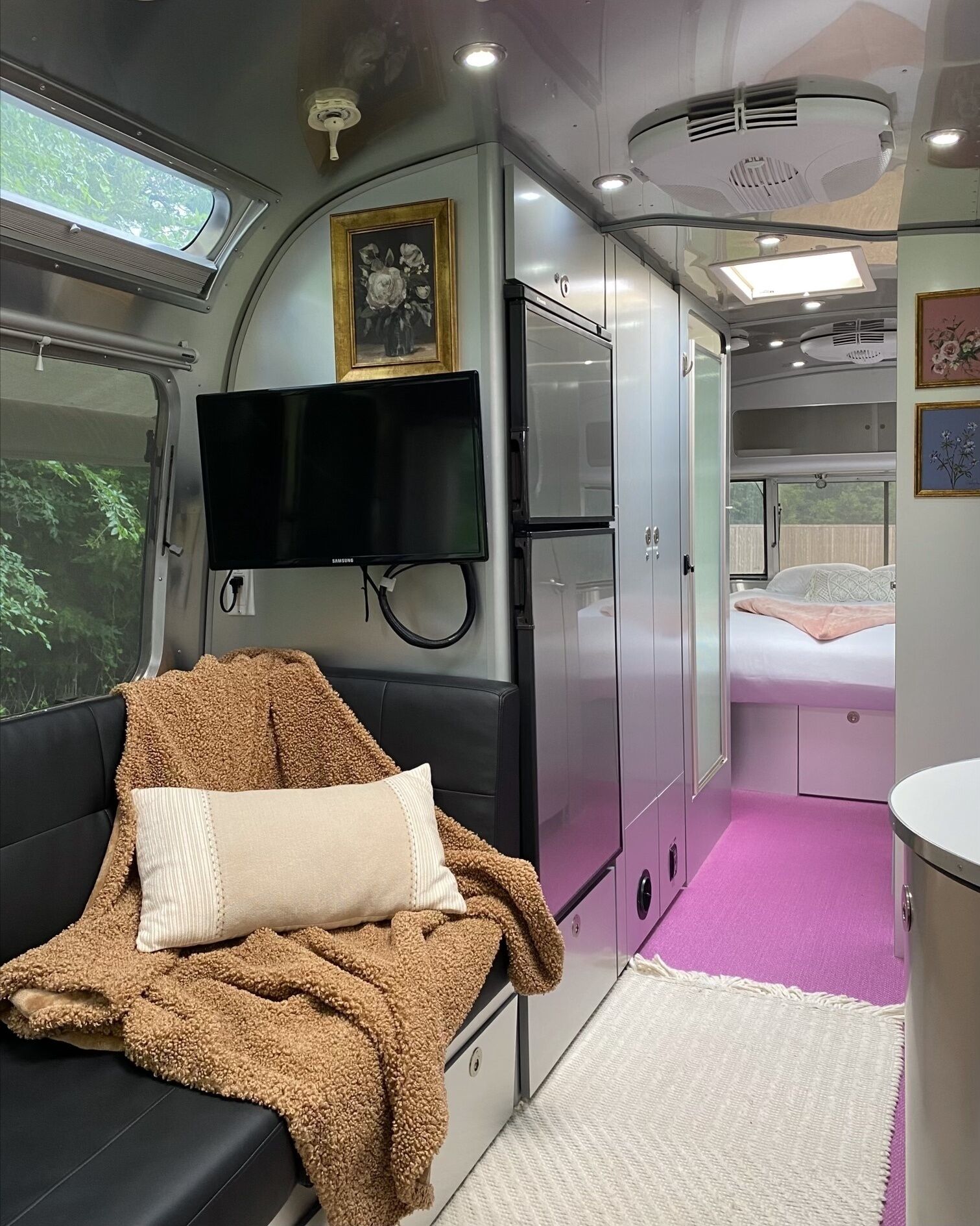 A compact train cabin with a sofa, a flat-screen TV, a bed, and a small bathroom.