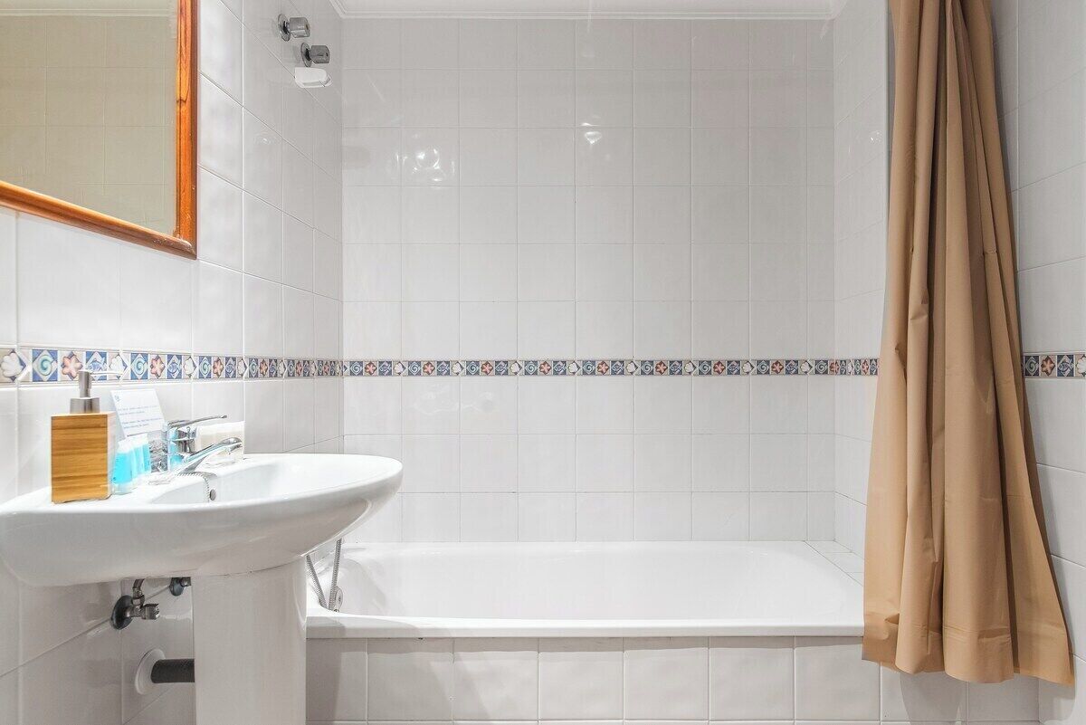 A bathroom with a white sink, a bathtub, and a shower curtain.